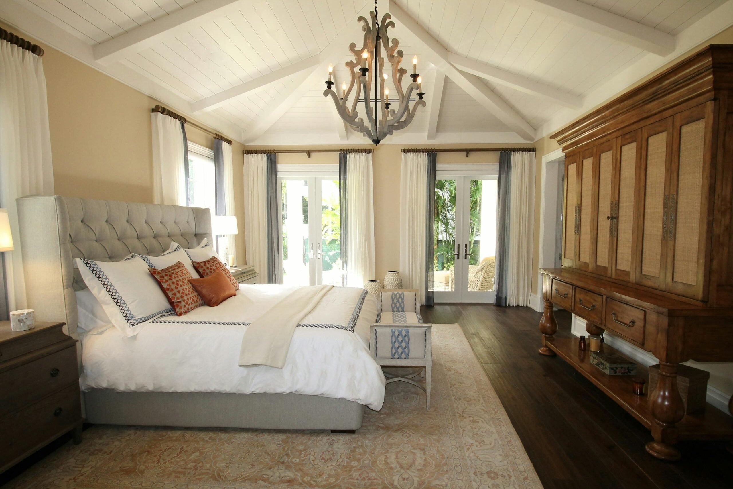 Stylish bedroom interior featuring a rustic chandelier, cozy bedding, and elegant wooden furniture.